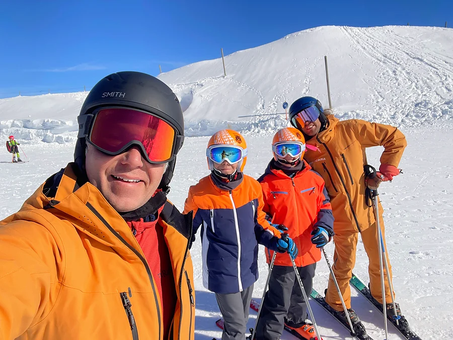 Dos niños con casco y dos profesores de Malacara en una pista de esquí.