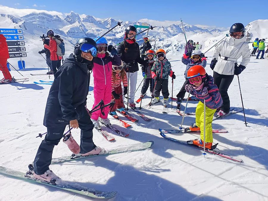Niños y acompañantes reunidos con sus esquís en una pista nevada.