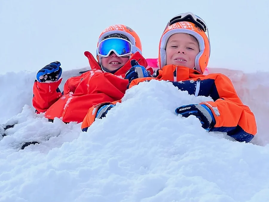 Dos niños con casco jugando en la nieve.