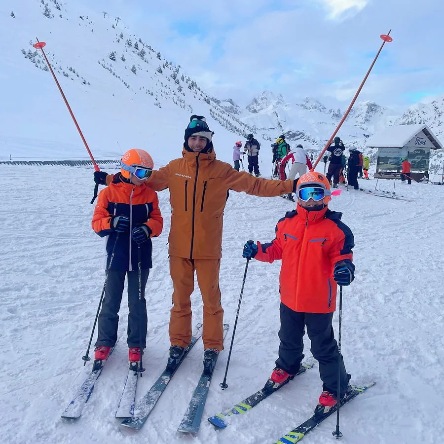 Profesor de Malacara con dos niños equipados para esquiar.
