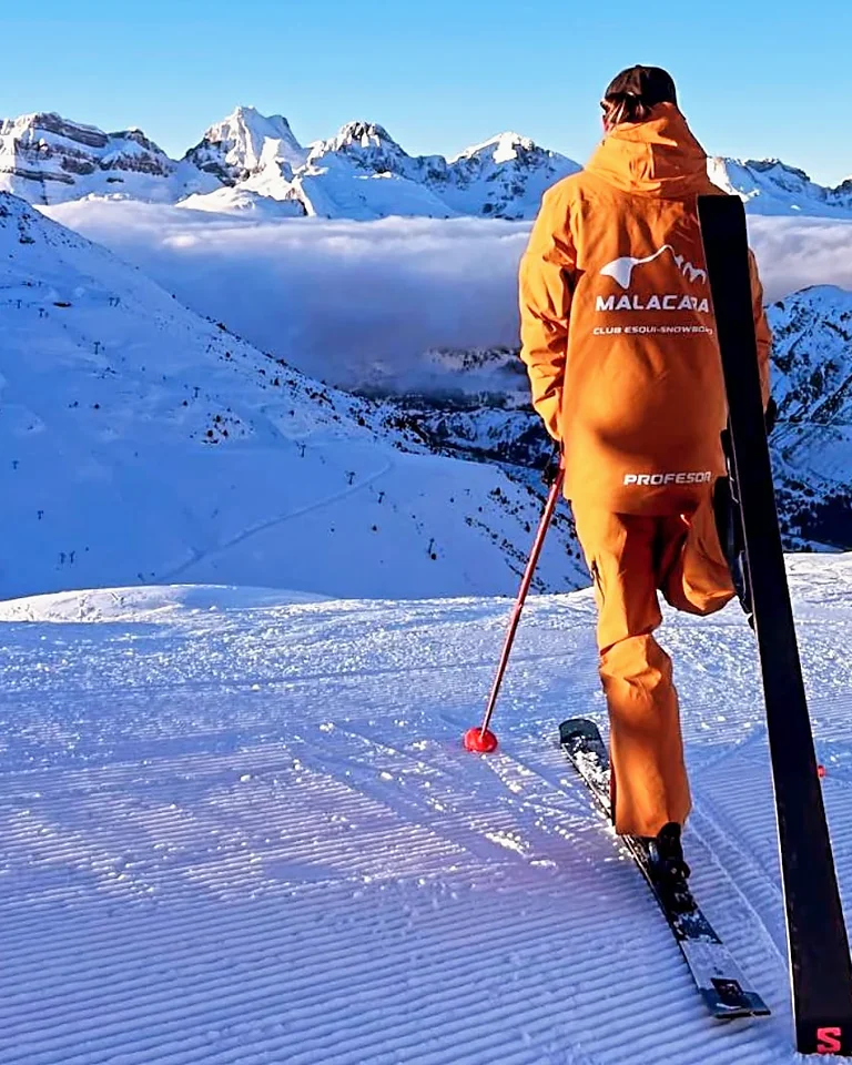 Profesor de Malacara con uniforme naranja en una pista nevada del Pirineo.